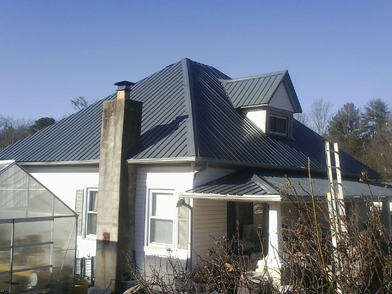 Dark blue standing seam metal roof on a white farmhouse with dormer — Slate & Tile Roof Repair by Roofing Brothers in Harpers Ferry