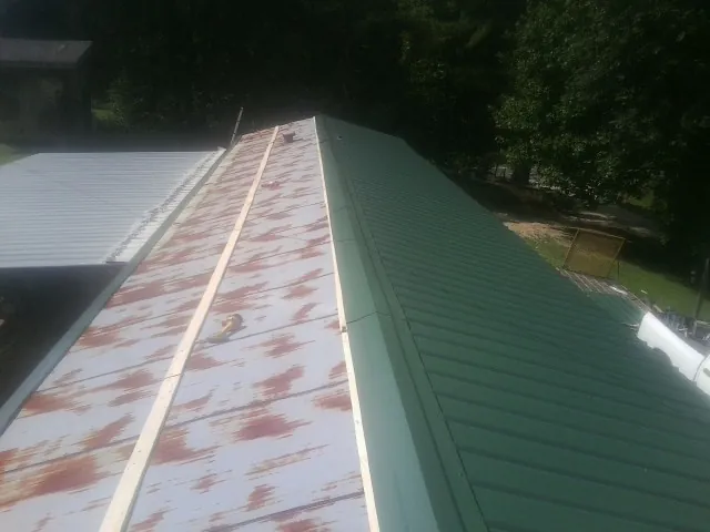 Old rusted panels beside newly installed green metal roofing — Wind Damage Roof Repair by Roofing Brothers in Harpers Ferry