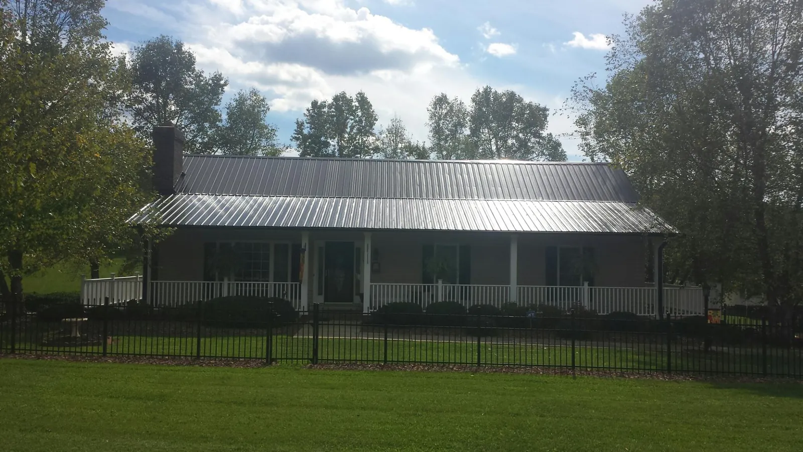 Gray metal roof on a brick ranch with a full width front porch — Gutter Guard Installation work by our crew in Harpers Ferry