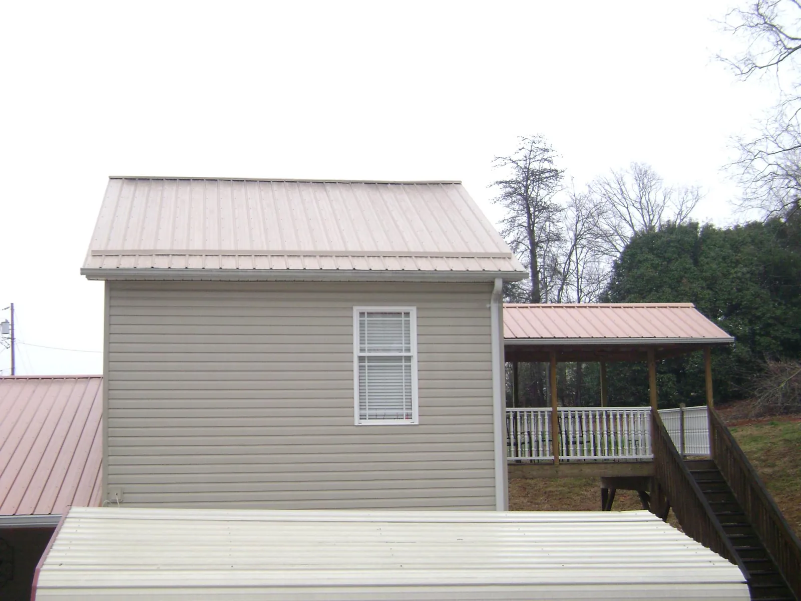 Tan metal roofs on a two story addition and attached porch, from a Roof Replacement job in Harpers Ferry