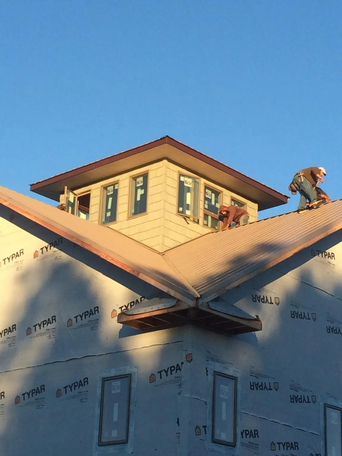 Roofers working around a rooftop cupola on a new metal roof at sunset — Roof Waterproofing in Harpers Ferry by Roofing Brothers